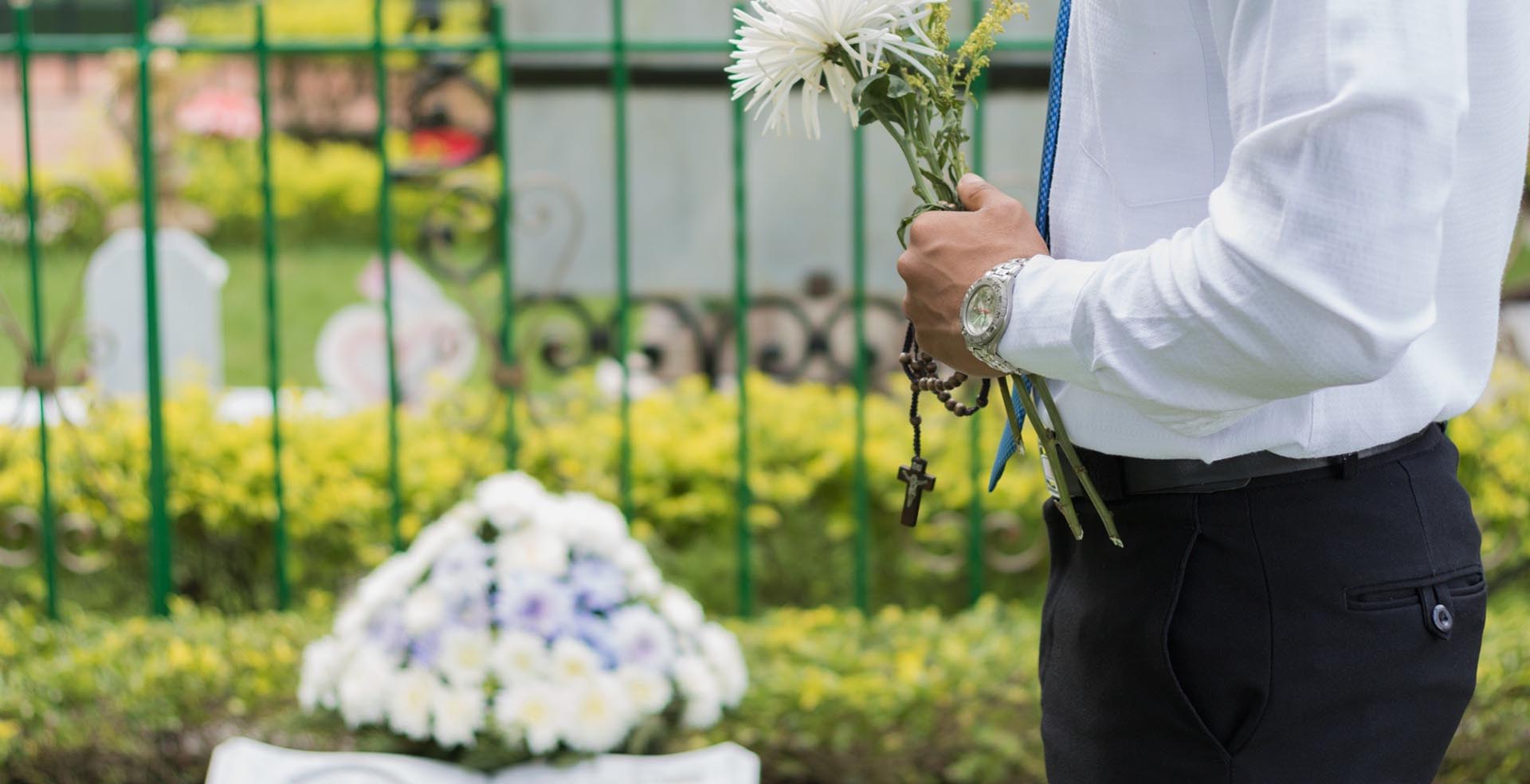 persona sosteniendo flores en un cementerio