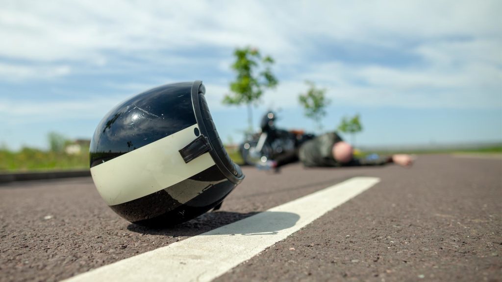 motorcycle helmet and rider lying on road